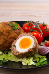 Scotch eggs on a plate with cherry tomatoes and salad, vertical