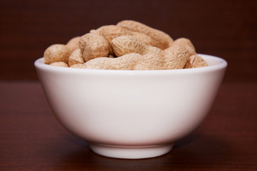 Peanuts uncleaned against a background of brown wood.