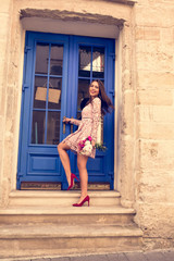 Fototapeta na wymiar Lovely brunette model in fashionable dress holding bouquet of flowers. Woman posing at the door.