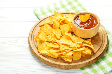 Spicy Mexican Nachos chips on a wooden tray. Tomato sauce. Flat