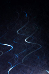 Abstract background of white curls in motion on black. Bokeh of defocused vertical curves, blurred neon leds, bright backdrop similar to magnetic field, power and electricity