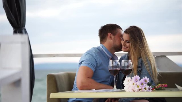 The husband and wife celebrate their anniversary in a restaurant near the water, a man and a woman drink wine in a cafe, a couple in love are happy with each other and talking