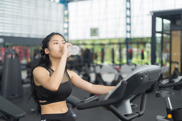 Fototapeta premium Fitness woman in training drinking water after exercises in gym