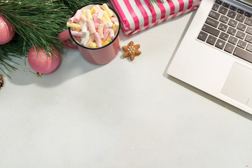 Chatting during Christmas and New Year holidays. Festive background of laptop near decorated pine and cup of marshmallows, top view. Greetings in social network concept