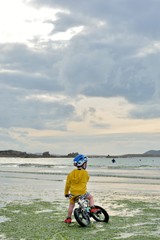 Fototapeta na wymiar Un petit garçon qui fait du vélo sur une plage en Bretagne