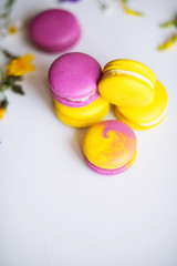 Morning cup of coffee, cake macaron and flower on light background from above. Beautiful breakfast. Flat lay style.
