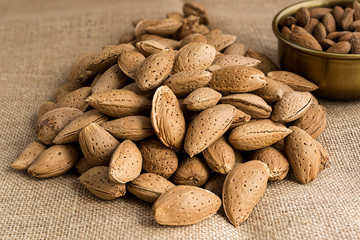 Almonds peeled in a bowl or in their nutshell on sackcloth