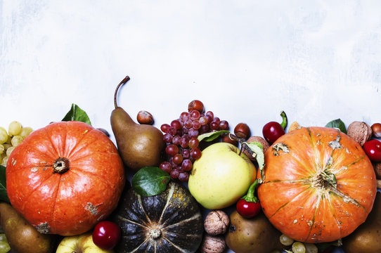 Autumn meal background with pumpkins, vegetables, fruits and nuts, thanksgiving concept, top view