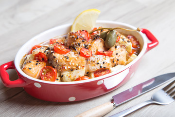 Salmon baked with sesame, tomatoes and zucchini. Close-up. Selective focus.