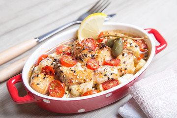 Salmon baked with sesame, tomatoes and zucchini. Close-up. Selective focus.