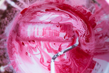 Red pink roller in a Paint bucket 
