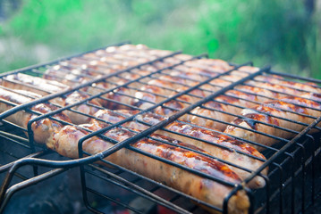 Cooking German sausages on the coals. Picnic.