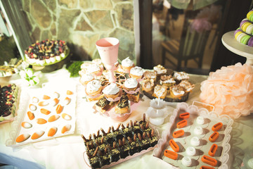 Delicious sweets on wedding candy buffet with desserts, cupcakes