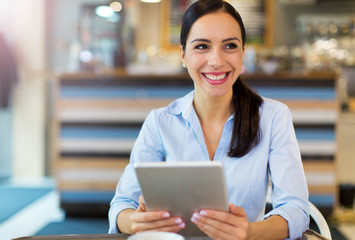 Plakat Woman using digital tablet in cafe 