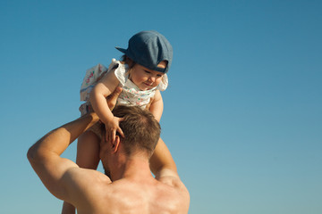 Father playing with his kid holding baby against the sky.