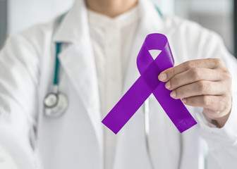 Plum purple ribbon for raising awareness on Alzheimer's disease, breastfeeding, eating disorder, national family caregivers month and epilepsy illness with bow in doctor’s hand support