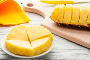 slices of a pineapple on white wooden background