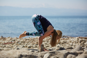 Yoga girl posing on cobblestone beach