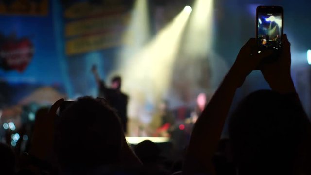 Evening concert. Crowd. People shoot video on a smartphone
