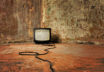 No Signal. An old TV with the noise on its display standing on the dirty floor, sepia color