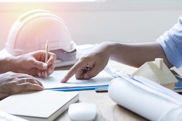 hand of engineer signing in contract paper and talking with colleagues about finance and success of company for building .