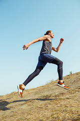 Running sport. Man runner sprinting outdoor in scenic nature. Fit muscular male athlete training trail running for marathon run.