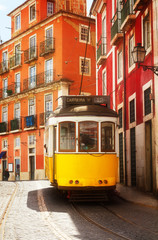 yellow tram on narrow street of Alfama, Lisbon, Portugal, retro toned