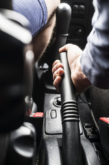 The man - driver holds the handbrake in the car. Close-up.