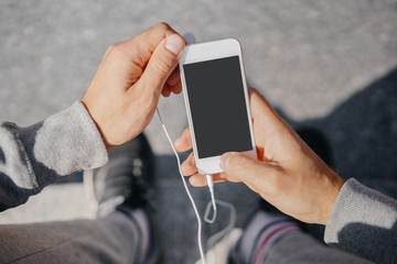 man athlete sitting on the street with mobile phone. City workout with smart gadgets and sport applications.