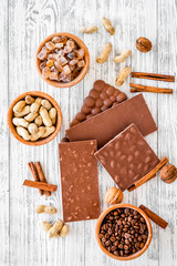 Chocolate bars of different varietes on grey wooden background top view