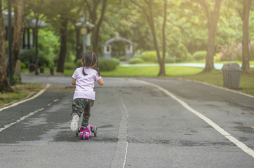 Fototapeta premium Child riding scooter in park or Behind child riding scooter