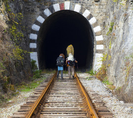 Family tourists with backpacks on railroad track