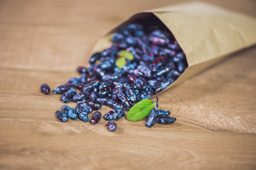 Fresh honeysuckle blue berry fruits with leaf on a wooden background