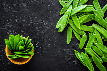 Green pea pods pattern on black background top view copyspace