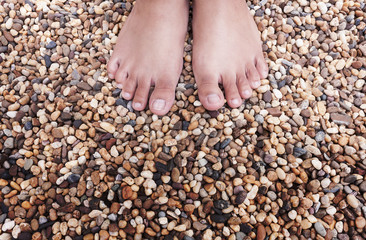 young woman foot of standing on colorful natural stones