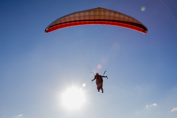 Paraglider flies in the blue sky.