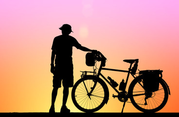 Obraz premium Silhouette man and vintage bike on blurry sunrise background