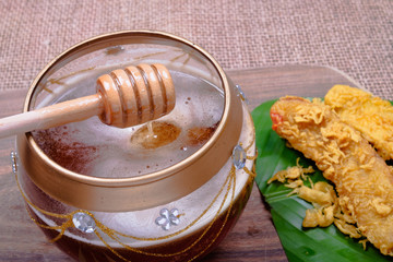 Honey dripping from wooden honey dipper and fried slices of the ripe BANANA also called Pisang Goreng, which are eaten as snack or used to accompany dishes in Malaysia