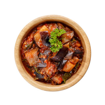 Stewed eggplant with tomatoes and herbs in wooden bowl isolated on white background.