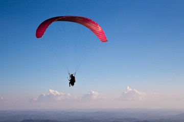 Paraglider flies in the blue sky.