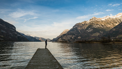 Lonely. A lone figure standing on the pier. Mountain landscape in the evening. Sad farewell.