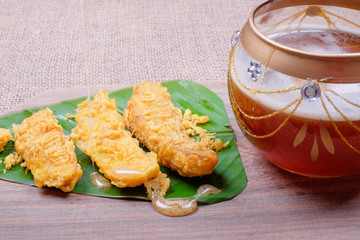 Honey dripping from wooden honey dipper and fried slices of the ripe BANANA also called Pisang Goreng, which are eaten as snack or used to accompany dishes in Malaysia