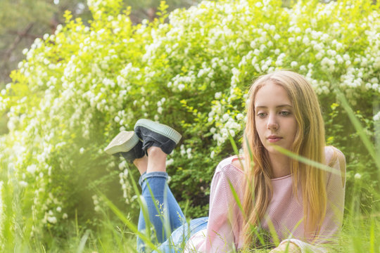 Cute blonde teenage-girl dreaming on a sunny day on the grass