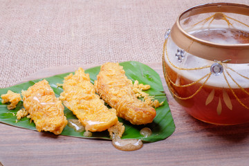 Honey dripping from wooden honey dipper and fried slices of the ripe BANANA also called Pisang Goreng, which are eaten as snack or used to accompany dishes in Malaysia