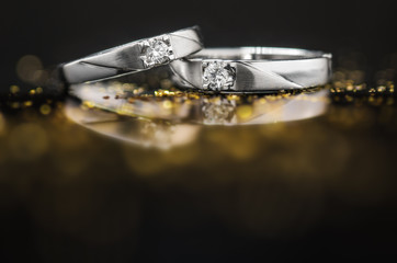 Close up pair of Platinum wedding rings with diamond on bokeh reflection background