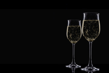 Two glasses champagne on a black background.