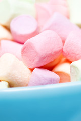 Colorful mini marshmallows in a blue bowl as background, macro. Fluffy marshmallows texture and pattern. High Resolution image, Soft focus