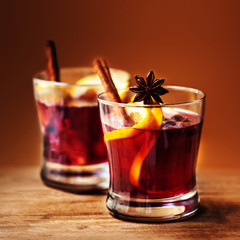 Christmas Hot mulled wine for winter with spices and orange slices on rustic table with copy space.  Red Hot wine or gluhwein with Christmas Decorations on wooden background, close up.