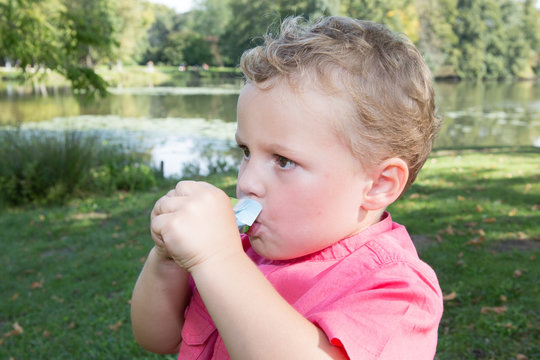 Child Sitting In The Grass Eating Applesauce In A Gourd