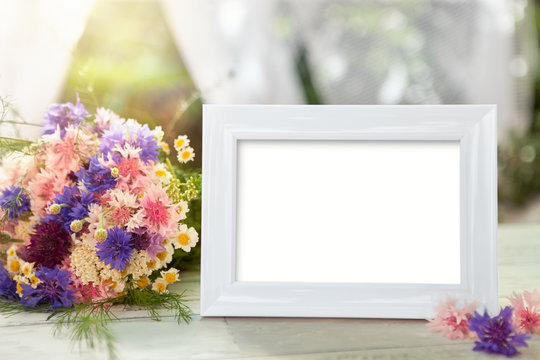 White frame and flowers on table